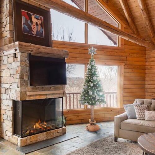 Choinka Sosna Diamentowa Na Pniu przystrojona w srebrne bombki na tle kominka z cegieł. - ujęcie 3