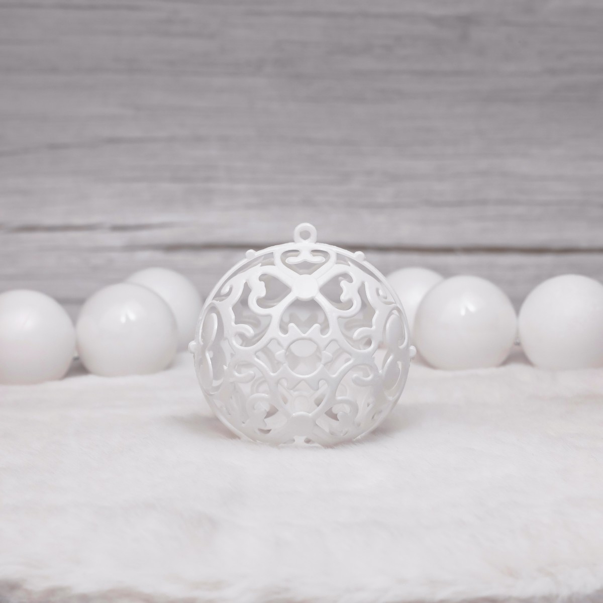 Zestaw zawiera bombki białe z wyciętą strukturą z symetrycznymi wzorami przypominające np. koronkę.