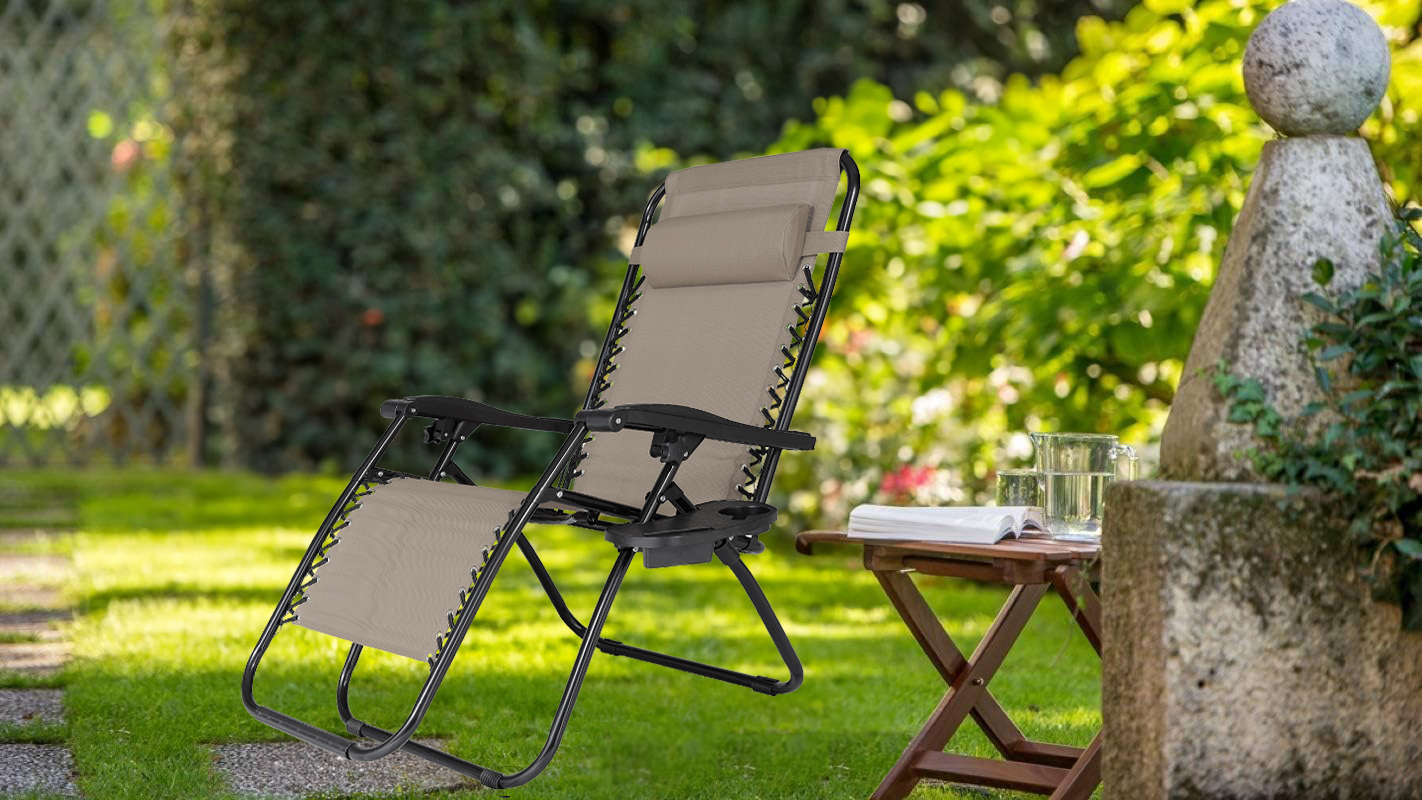 Beżowo-czarny leżak NO GRAVITY w pozycji leżącej na tle ogrodu.